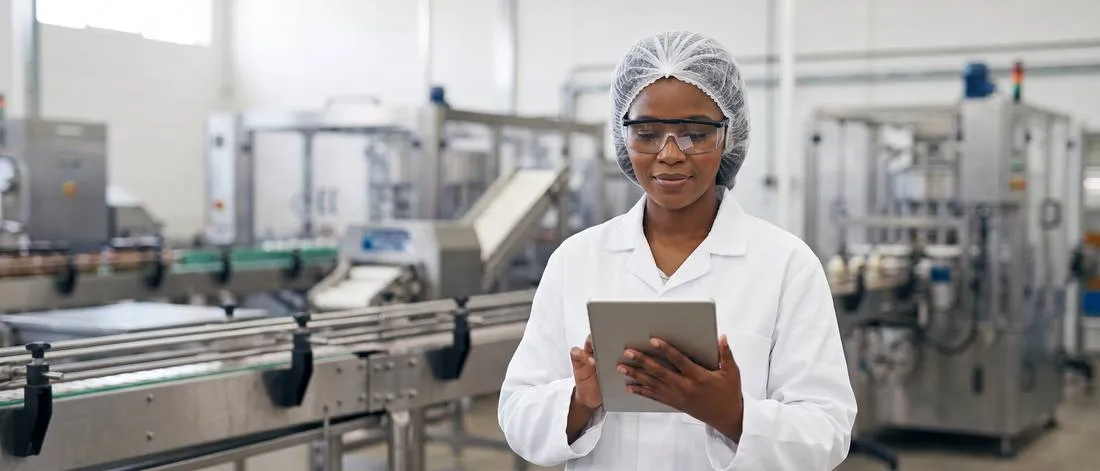 Quality assurance professional using a tablet on a food and beverage production floor